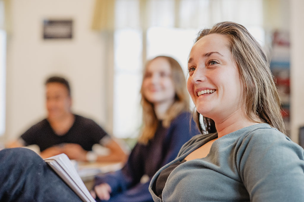 Leende deltagare på folkhögskola i ett klassrum.