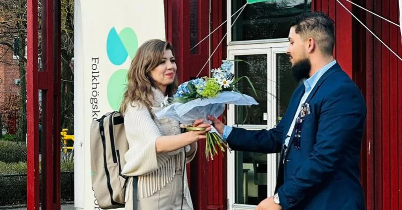 En kvinna lämnar över blommor till en ung man.