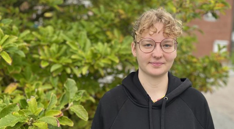 Person med runda glasögon och svart luvtröja.