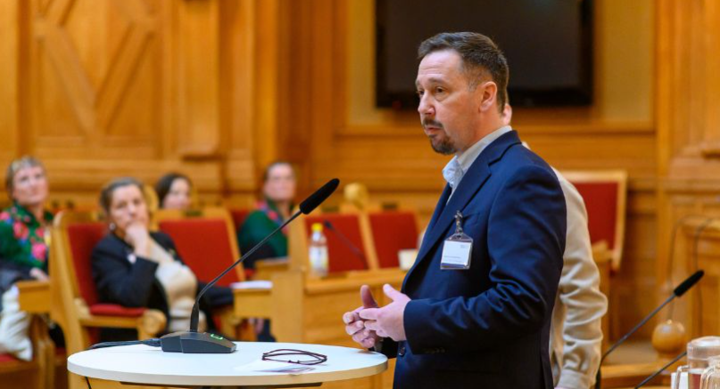 En man i en talarstol inför publik.